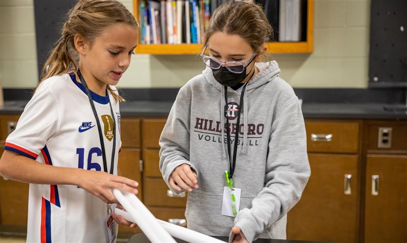Two students work on a mini rollercoaster track